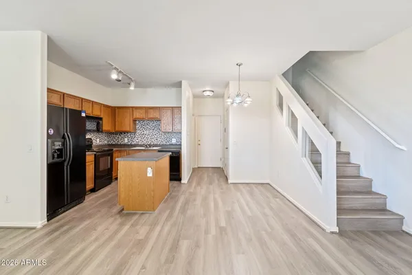 a kitchen with stainless steel appliances granite countertop a refrigerator a sink dishwasher a stove and a wooden floors