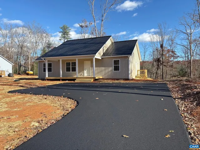 a front view of house with yard outdoor seating and covered with trees