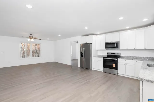 an empty room with wooden floor closet and windows