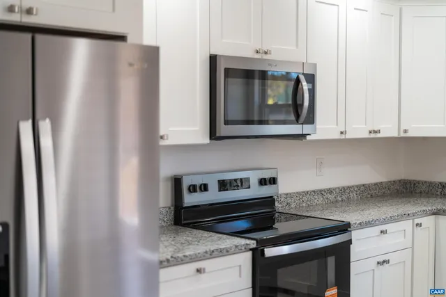 a kitchen with granite countertop white cabinets and stainless steel appliances