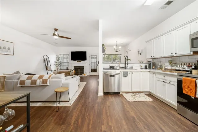 a kitchen with stainless steel appliances granite countertop a stove top oven a sink dishwasher and a microwave oven on the wooden floor