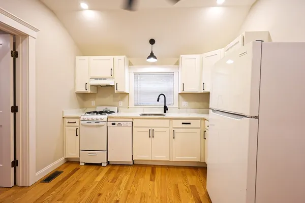 a kitchen with stainless steel appliances a sink and wooden floor