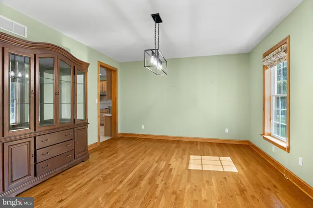 a view of an empty room with window and chandelier fan