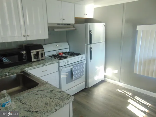 a kitchen with stainless steel appliances granite countertop a refrigerator a stove and a sink