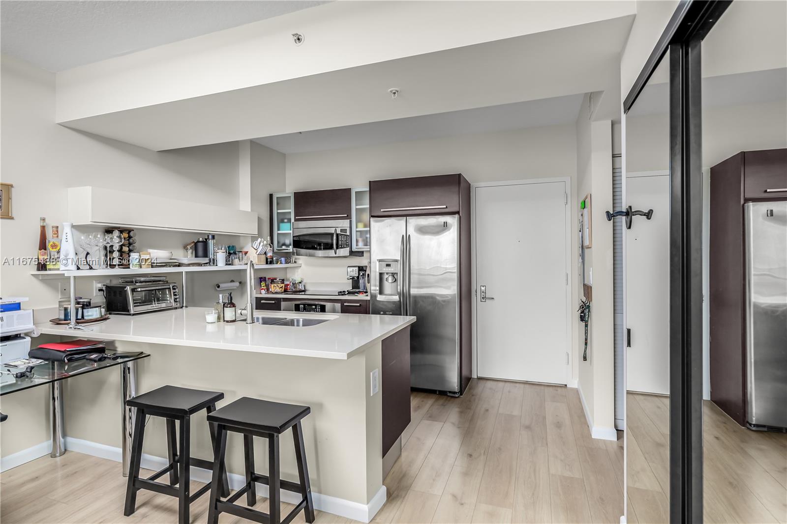 333 Northeast 24th Street, Unit 1206 Miami, FL 33137 - Photo 9 of 26 a kitchen with stainless steel appliances a stove a refrigerator and a refrigerator with wooden floor