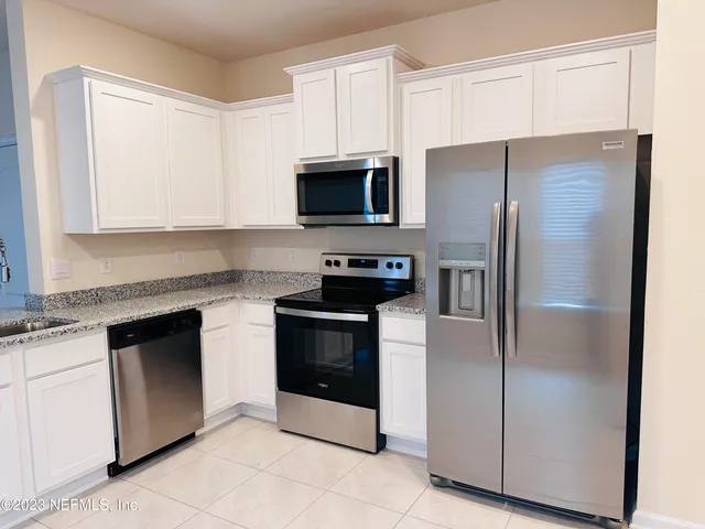 a kitchen with stainless steel appliances granite countertop a refrigerator stove a sink and a microwave