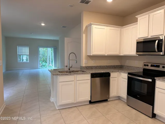a kitchen with stainless steel appliances granite countertop a stove a sink and a microwave
