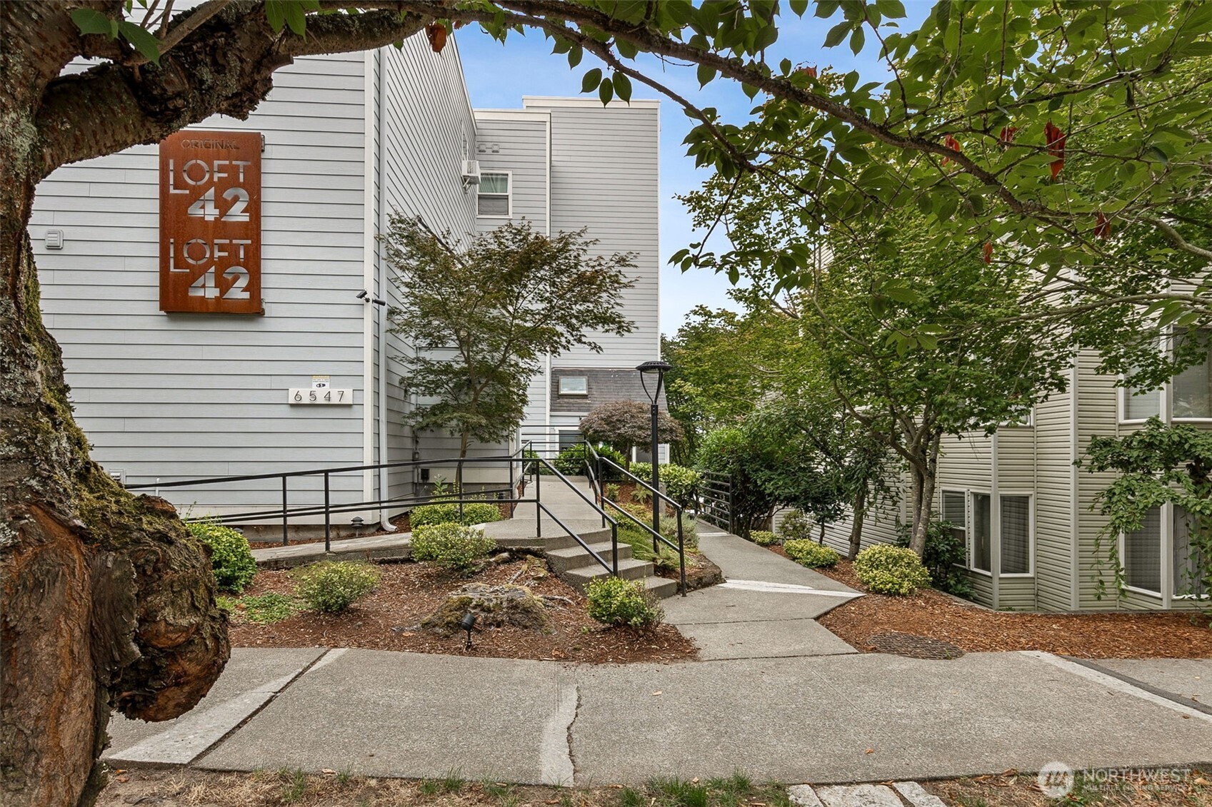 6547 42nd Avenue Southwest, Unit 205 Seattle, WA 98136 - Photo 2 of 18 a view of a house with a yard and tree s