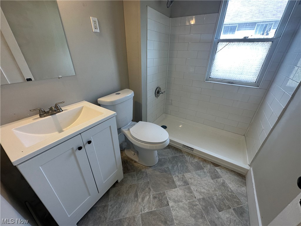10820 Bellaire Road Cleveland, OH 44111 - Photo 16 of 24 Bathroom featuring dark tile floors, vanity, mirror, and tiled shower