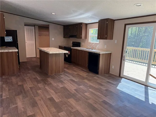 a large kitchen with a sink and dishwasher a stove top oven with wooden floor