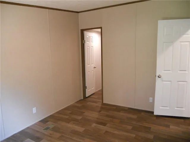 a view of an empty room with wooden floor and closet