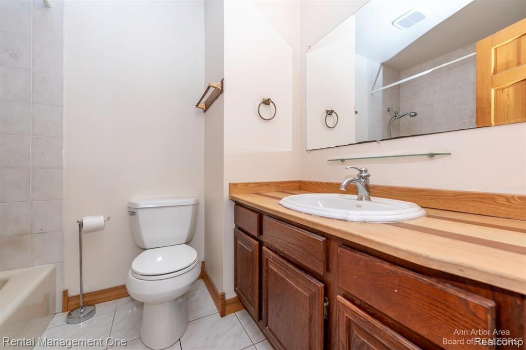 7870 Chamberlin Road Dexter, MI 48130 - Photo 29 of 52 Wood-finish vanity with an integrated sink, polished chrome faucet, and expansive wall-mounted mirror