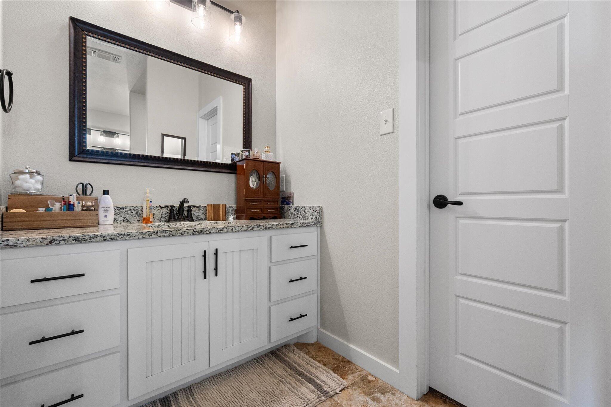 3263 Quail Road Lubbock, TX 79407 - Photo 18 of 46 a bathroom with a granite countertop sink and a mirror