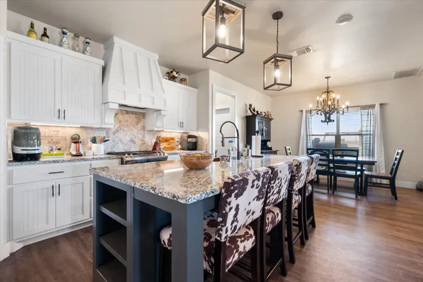 a kitchen with stainless steel appliances granite countertop a stove top oven a refrigerator a sink dishwasher and white cabinets with wooden floor