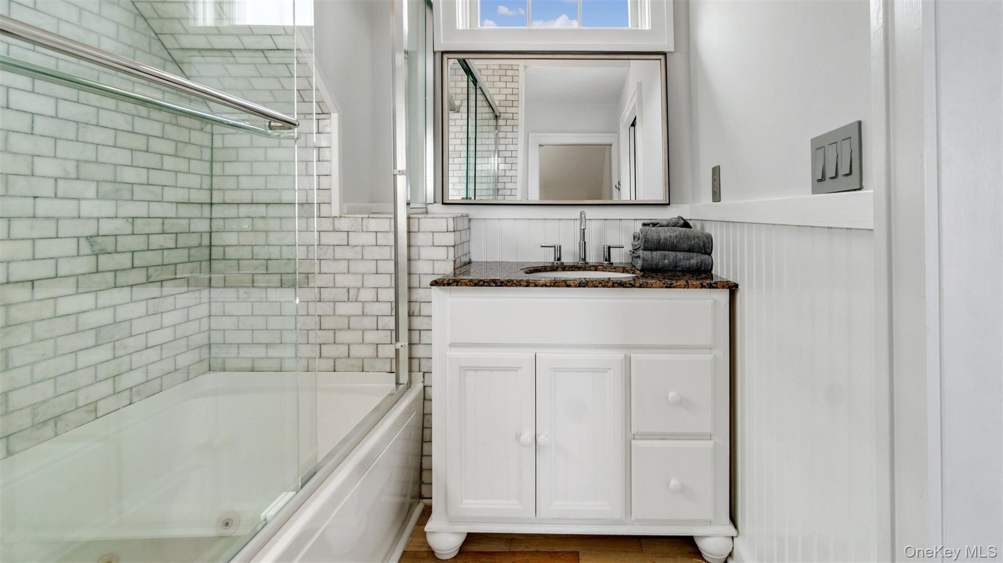 12910 Main Road East Marion, NY 11939 - Photo 20 of 41 a bathroom with a granite countertop sink a mirror and a bathtub
