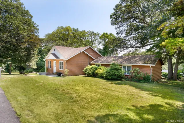 a view of a house with a big yard and large trees
