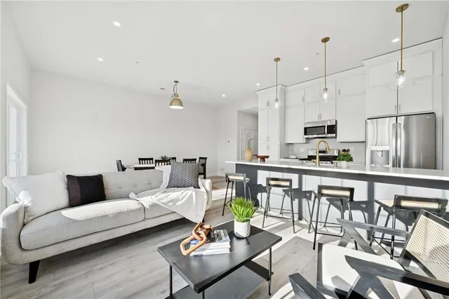 a living room with furniture kitchen and a wooden floor