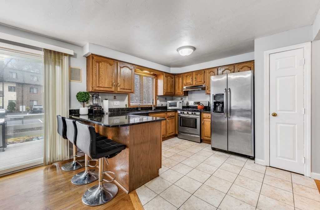 a kitchen with granite countertop a refrigerator a stove a sink and cabinets