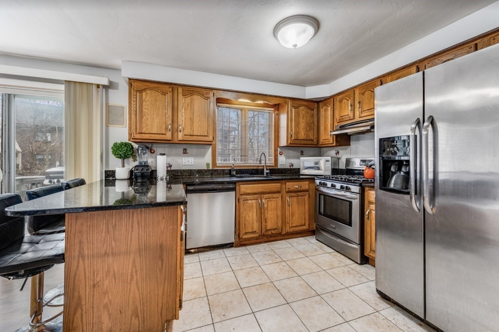 105 Irving Road, Unit 105 Randolph, MA 02368 - Photo 2 of 17 a kitchen with granite countertop a refrigerator a sink a stove and cabinets