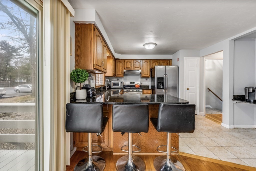 105 Irving Road, Unit 105 Randolph, MA 02368 - Photo 3 of 17 a kitchen with stainless steel appliances kitchen island granite countertop a table and chairs