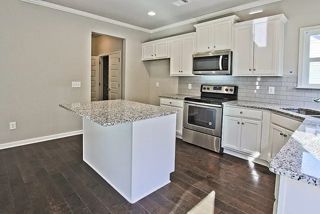 a kitchen with stainless steel appliances granite countertop a stove a sink and a microwave