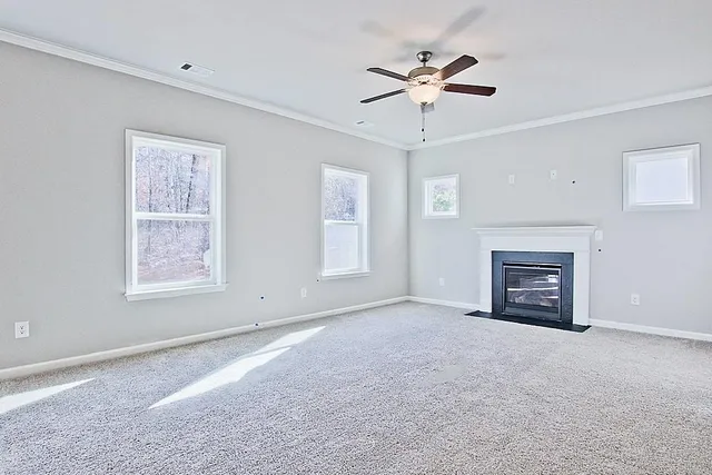 a view of livingroom with a fireplace ceiling fan and windows