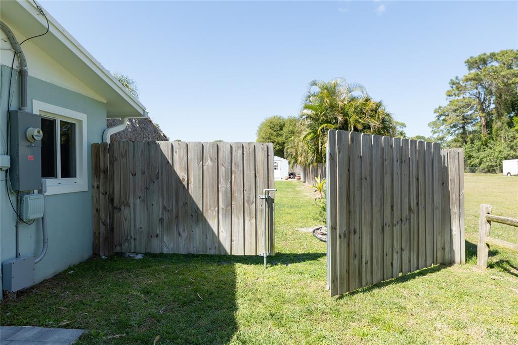 1497 Southwest Buckskin Trail Stuart, FL 34997 - Photo 44 of 48 a backyard of a house with plants and wooden fence