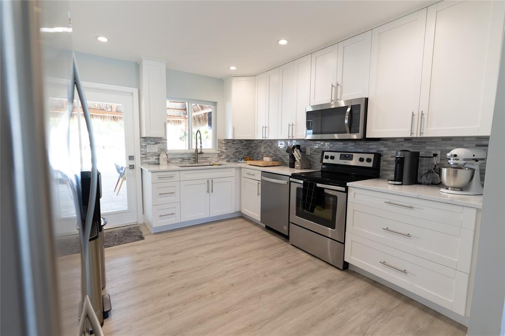 1497 Southwest Buckskin Trail Stuart, FL 34997 - Photo 9 of 48 a kitchen with stainless steel appliances granite countertop a stove top oven a refrigerator and a sink