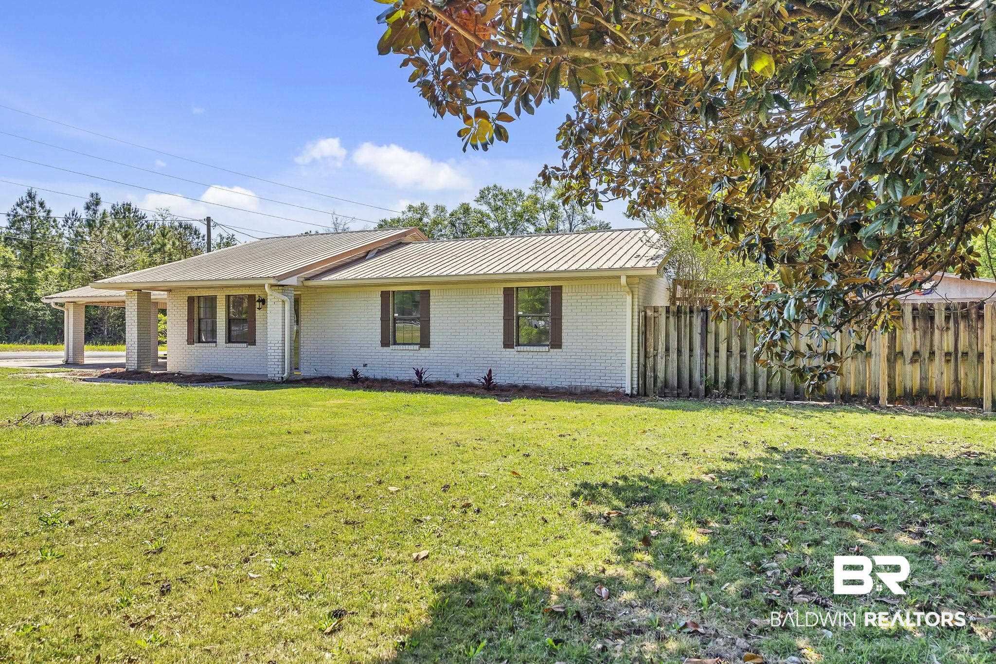 11964 Stroh Road Daphne, AL 36527 - Photo 4 of 58 View of front of house featuring brick siding, fence, a front lawn, and metal roof