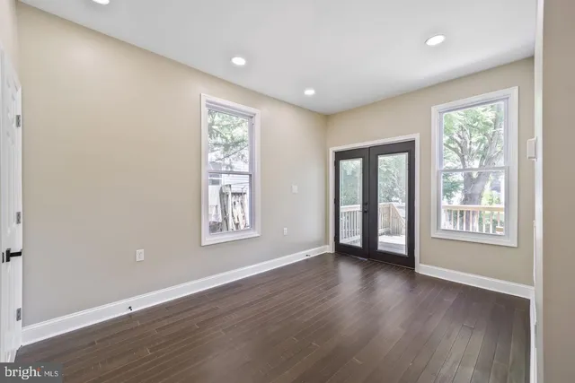a view of an empty room with wooden floor and windows