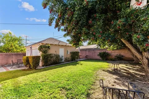 a view of a backyard with table and chairs potted plants and large tree
