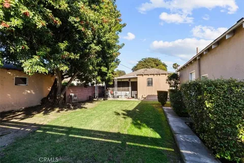 a view of a house with a big yard plants and large trees