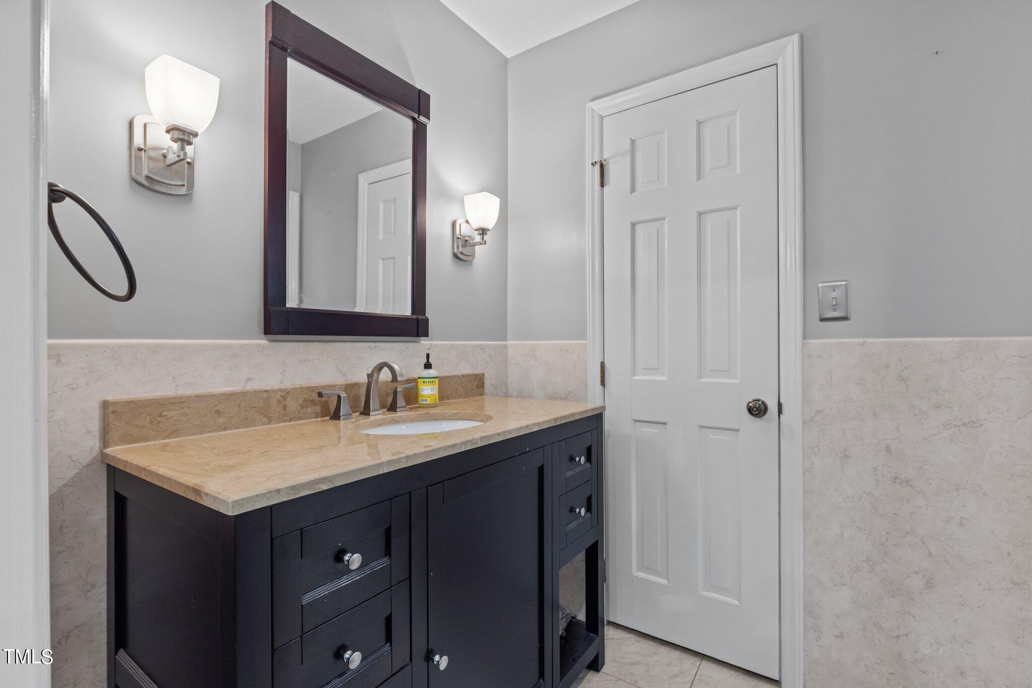 8809 Leesville Road Raleigh, NC 27613 - Photo 21 of 32 a bathroom with a granite countertop sink vanity and a mirror