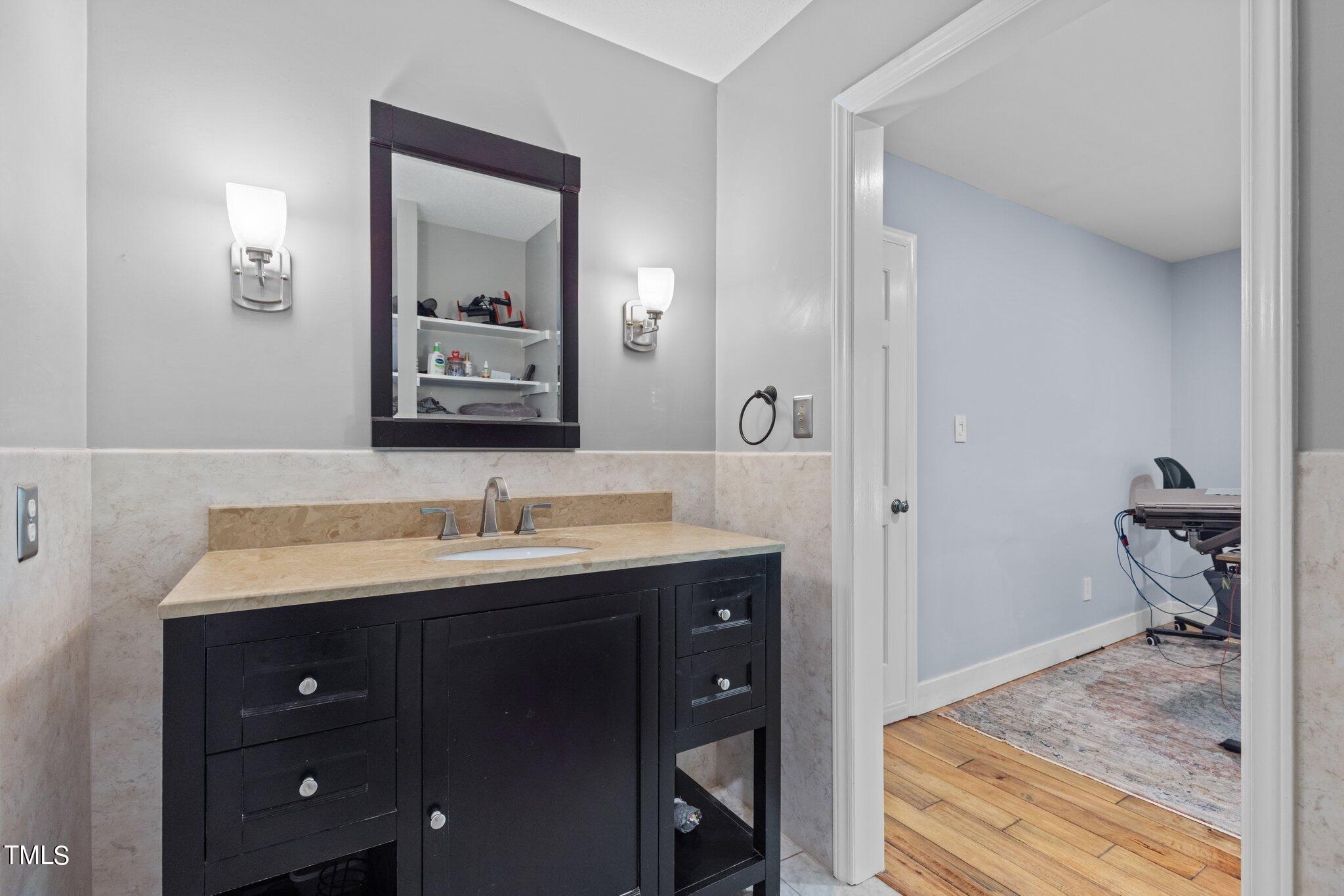 8809 Leesville Road Raleigh, NC 27613 - Photo 23 of 32 a en suite bathroom with a granite countertop sink and a mirror