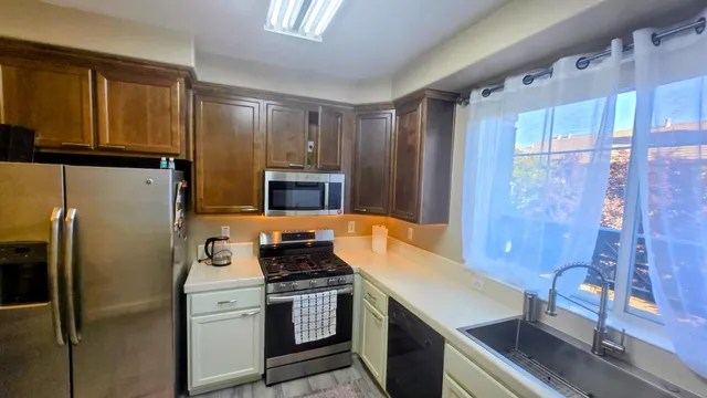 a kitchen with stainless steel appliances granite countertop a refrigerator a stove and a sink