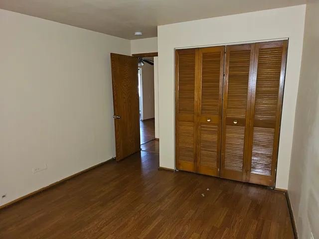 an empty room with wooden floor and closet area