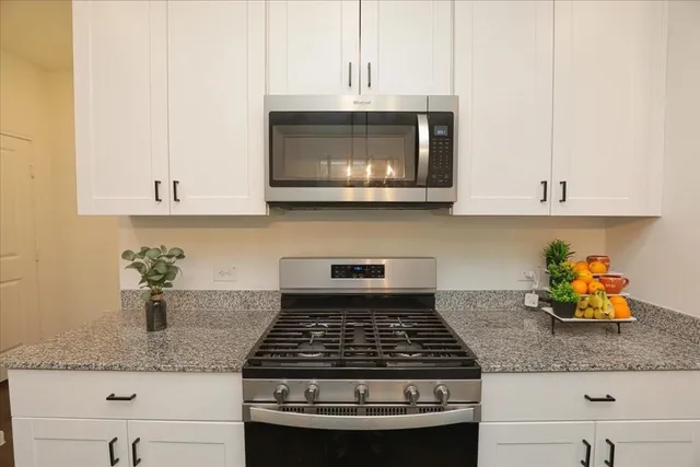 a kitchen with granite countertop stainless steel appliances stove top oven and cabinets