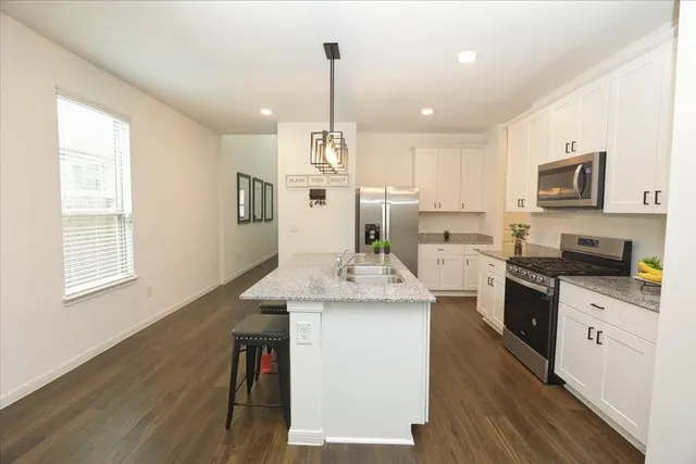 a kitchen with stainless steel appliances kitchen island granite countertop a stove a sink and a wooden floors
