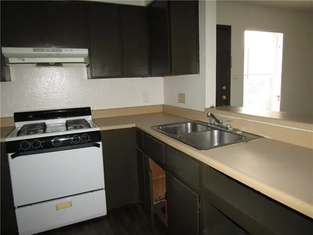 a kitchen with a sink a stove and cabinets