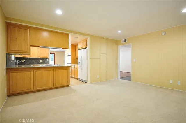 a view of kitchen with refrigerator cabinets and a sink