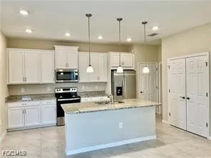 a large kitchen with stainless steel appliances kitchen island granite countertop a stove a sink a refrigerator and white cabinets