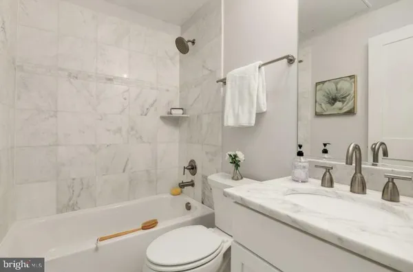 a bathroom with a granite countertop sink a toilet and bathtub