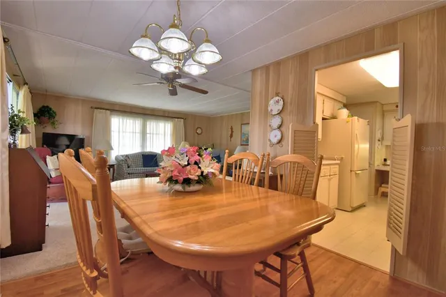 a dining room with wooden floor a chandelier a wooden table and chairs