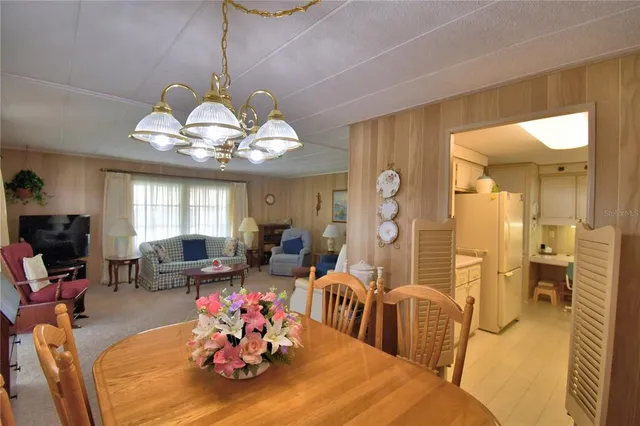a view of a dining room with furniture a chandelier and large windows