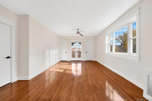 a view of empty room with wooden floor and fan