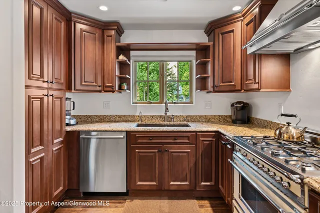 a kitchen with stainless steel appliances granite countertop a stove a sink and a microwave