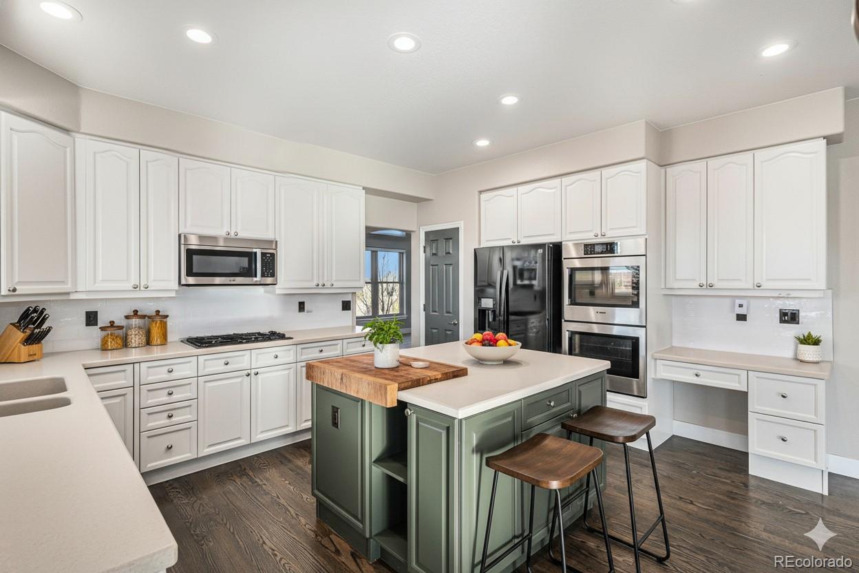 12665 South Robinson Ranch Boulevard Parker, CO 80134 - Photo 12 of 38 a view of kitchen with stainless steel appliances granite countertop a stove top oven a refrigerator a stove and white cabinets with wooden floor