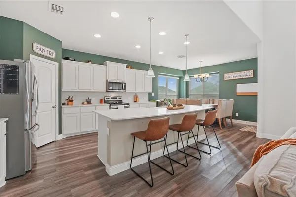 a kitchen with stainless steel appliances granite countertop a sink a stove a refrigerator and island with wooden floor