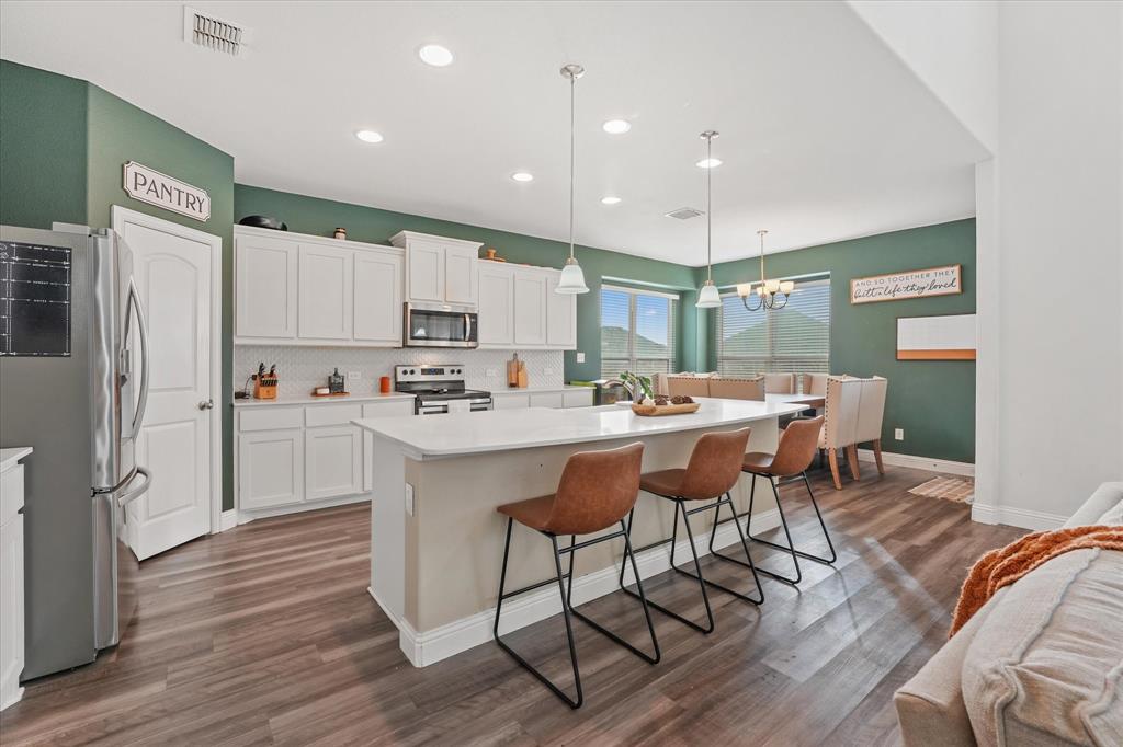 3725 Ranchers Ridge Krum, TX 76249 - Photo 18 of 38 a kitchen with stainless steel appliances granite countertop a sink a stove a refrigerator and island with wooden floor