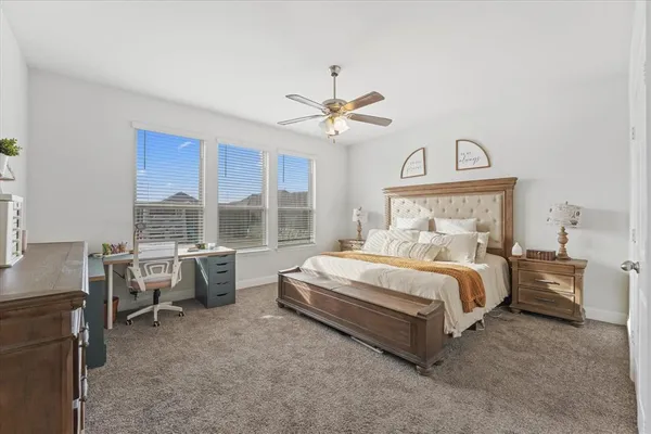 a spacious bedroom with a bed a chandelier and a large window